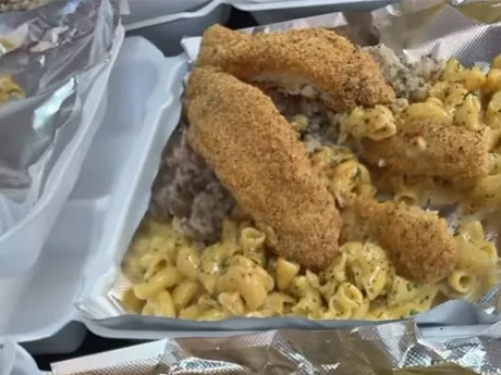 Cornmeal-crusted fish fillets on mac and cheese and rice in a foil-lined box